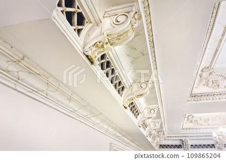 White plaster molding elements with gold veins for decorating the ceiling in a classic style 109865204