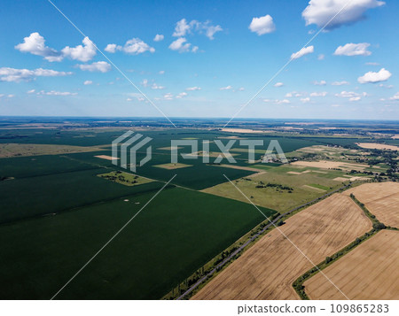 Beautiful agricultural landscape, open field with blue sky and white clouds. Farmfields from a bird's eye view. Beautiful agricultural landscape, open field with blue sky and white clouds. Farmfields from a bird's eye view. 109865283