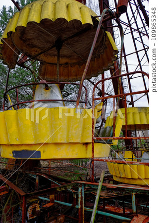 A weathered ferris wheel stands tall amidst bare trees. A weathered ferris wheel stands tall amidst bare trees. 109865348