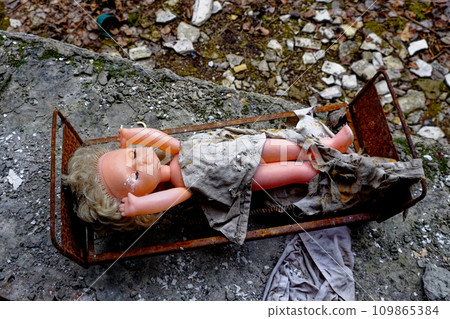 A discarded doll lies in a rusty bed amidst debris. A discarded doll lies in a rusty bed amidst debris. 109865384