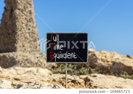 FTE Full time equivalent symbol. Concept words FTE Full time equivalent on beautiful black chalk blackboard. Beautiful stone beach background. Business and FTE Full time equivalent concept. Copy space 109865723