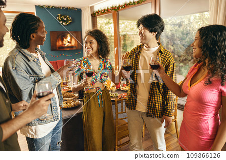Cheerful friends enjoying in conversation and drinking wine during festive dinner at home party Cheerful friends enjoying in conversation and drinking wine during festive dinner at home party 109866126