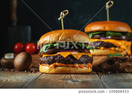 Two delicious homemade burgers of beef, cheese and mushrooms on an wooden table. Fat unhealthy food 109866433