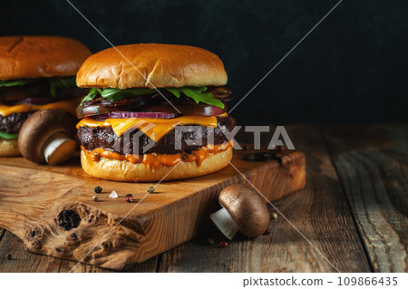 Two delicious homemade burgers of beef, cheese and mushrooms on an wooden table. With copy space 109866435