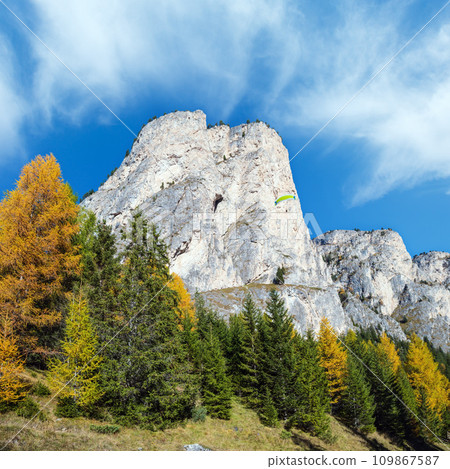 Autumn alpine Dolomites mountain scene and unrecognizable paragliders in sky. Peaceful view near Wolkenstein in Groden, Selva di Val Gardena, Sudtirol, Italy. Autumn alpine Dolomites mountain scene and unrecognizable paragliders in sky. Peaceful view near Wolkenstein in Groden, Selva di Val Gardena, Sudtirol, Italy. 109867587