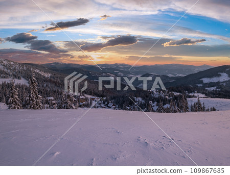 Picturesque winter  morning pre sunrise alps. View of famous Ukrainian Dragobrat ski resort from Svydovets mountain ridge. 109867685