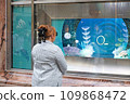 pretty woman in beautiful clothes looks at a store window 109868472