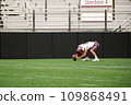 sportsman american football player leaned over with the ball 109868491
