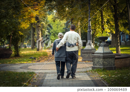 An elderly couple, man and woman walk in the autumn park. An elderly couple, man and woman walk in the autumn park. 109869489