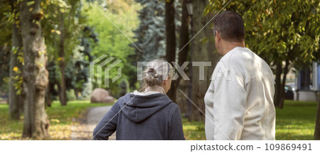 An elderly couple, man and woman walk in the autumn park. An elderly couple, man and woman walk in the autumn park. 109869491