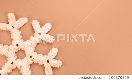Fluffy white snowflake Christmas decor. Image toned in Peach Fuzz color of the year 2024. The concept of New Year and Christmas holidays, congratulations. Copy space. View from above 109870529