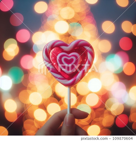 Hand holding colorful Lollipop heart shape on the stick with bokeh background.  109870604