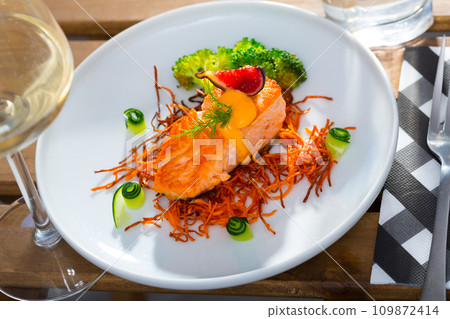 Tasty fried salmon on a pillow of smoked carrots, broccoli and fig on plate Tasty fried salmon on a pillow of smoked carrots, broccoli and fig on plate 109872414