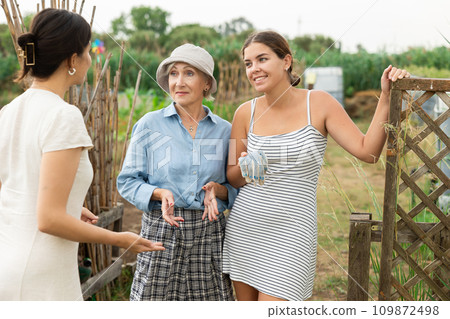 Three women chatting in the backyard of country house 109872498