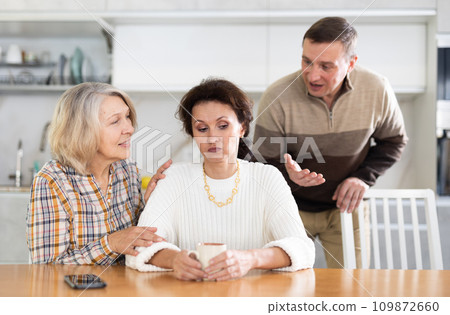 Family members quarreling in the kitchen and old woman trying to calm angry woman 109872660