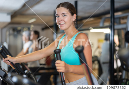Young woman working out on elliptical machine 109872862