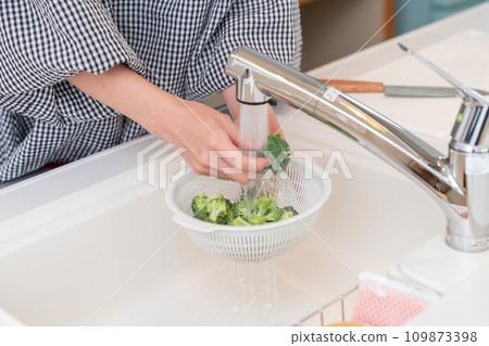 Woman cooking, washing broccoli at hand 109873398