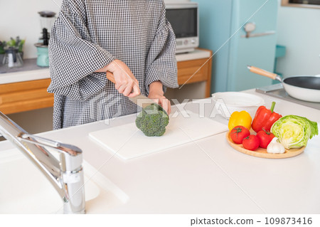 Woman cooking, cutting broccoli at hand 109873416