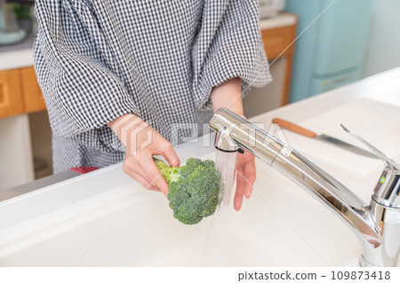 Woman cooking, washing broccoli at hand 109873418