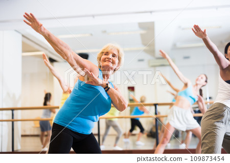 Portrait of mature woman practicing ballet dance moves during group class in choreographic studio Portrait of mature woman practicing ballet dance moves during group class in choreographic studio 109873454