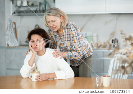 Elderly mother calms her daughter down and asks her for forgiveness after a domestic quarrel in kitchen 109873534