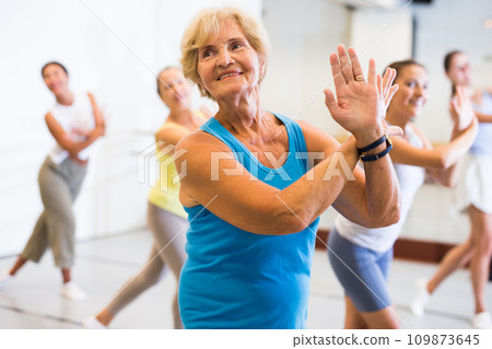 Portrait of mature woman practicing ballet dance moves during group class in choreographic studio Portrait of mature woman practicing ballet dance moves during group class in choreographic studio 109873645