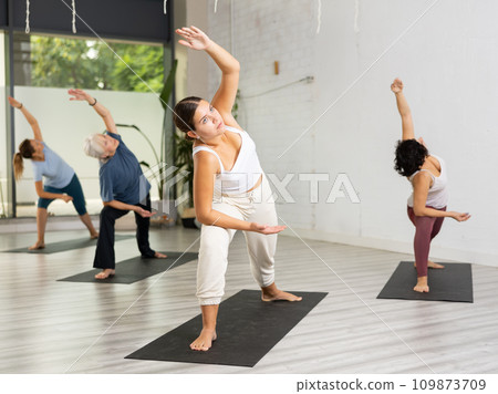 Women practicing yoga - virabhadrasana pose 109873709