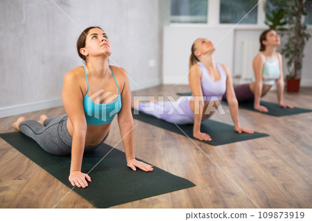 Girl doing Urdhva Mukha Shvanasana during group yoga workout 109873919