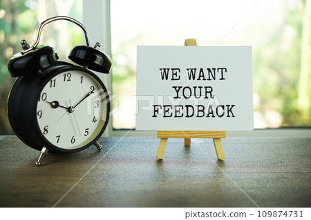 We want your feedback text message on paper card with wooden easel on wooden table background We want your feedback text message on paper card with wooden easel on wooden table background 109874731