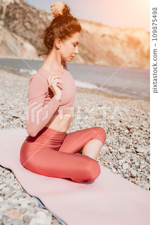 Middle aged well looking woman with black hair, fitness instructor in leggings and tops doing stretching and pilates on yoga mat near the sea. Female fitness yoga routine concept. Healthy lifestyle 109875498