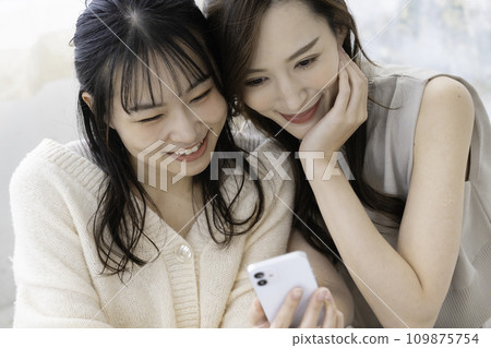 Close sisters using smartphones Close sisters using smartphones 109875754