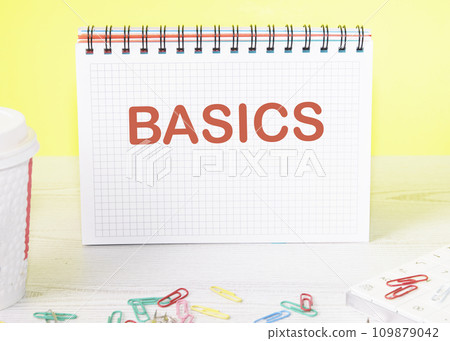 BASICS the word is written on a blank sheet in a notebook standing on a table on a yellow background BASICS the word is written on a blank sheet in a notebook standing on a table on a yellow background 109879042