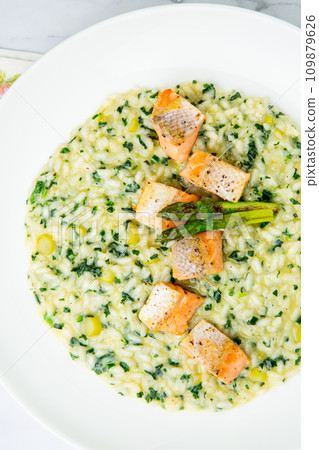 rice porridge with artichoke, red fish and herbs in a white plate, top view 109879626