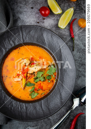 spicy tom yum in a black plate with greens, top view 109879669