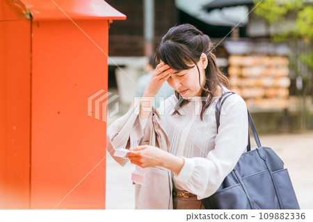 Asian woman drawing a fortune at a shrine Asian woman drawing a fortune at a shrine 109882336