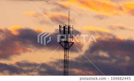 Telecommunications tower with beautiful sky at sunrise. Electronic antenna with clouds and orange sky background. Modern business communication Telecommunications tower with beautiful sky at sunrise. Electronic antenna with clouds and orange sky background. Modern business communication 109882445