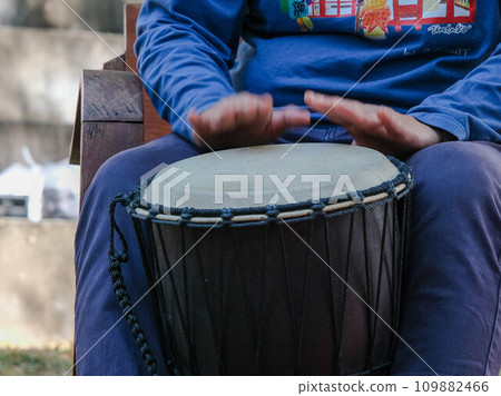 Asian man playing rhythmic instrument. A man plays a long drum at a party. Thai musical instruments 109882466