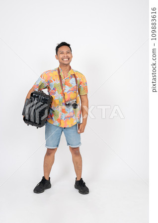 A happy Asian man tourist in summer clothes is carrying his luggage, on an isolated white background 109883616