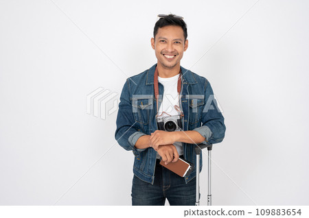 A positive Asian man with his passport and luggage is standing on an isolated white background. 109883654