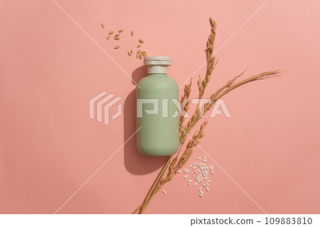 An unlabeled cosmetic bottle and rice are displayed on a pink background. Blank space for design. Cosmetic mockup with natural ingredients. Advertising space. An unlabeled cosmetic bottle and rice are displayed on a pink background. Blank space for design. Cosmetic mockup with natural ingredients. Advertising space. 109883810