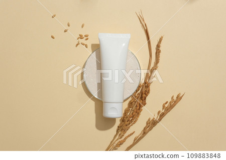 Unbranded cosmetic tube stands out on a minimalist beige background. Creating a vegan cosmetics brand featuring key ingredients sourced from rice bran. Copy space. Unbranded cosmetic tube stands out on a minimalist beige background. Creating a vegan cosmetics brand featuring key ingredients sourced from rice bran. Copy space. 109883848
