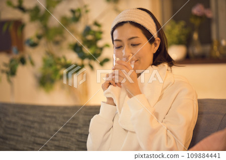 Night routine of a woman drinking water after taking a bath Night routine of a woman drinking water after taking a bath 109884441