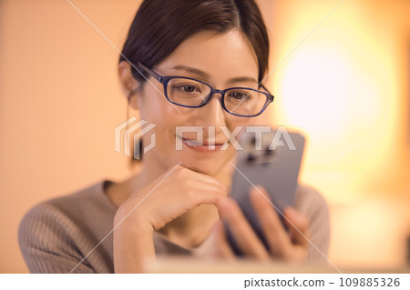 女人在客廳看智慧型手機 夜間例行公事 109885326