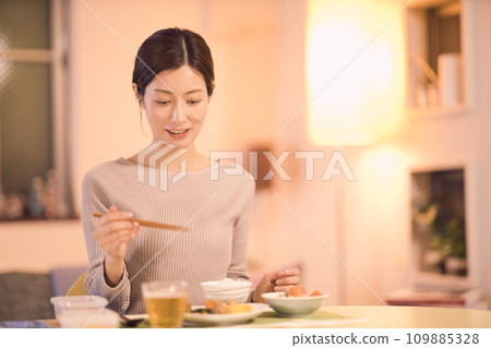 Night routine of a business woman who eats dinner with prepared dishes Night routine of a business woman who eats dinner with prepared dishes 109885328