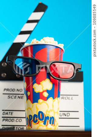 Movie clapper, pop corn, 3D glasses and film reel on blue background. Collage design 109885549