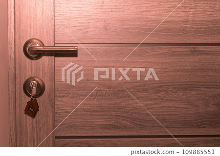 Buy Or Rent concept. Keys with trinket in shape of house in the door keyhole. 109885551