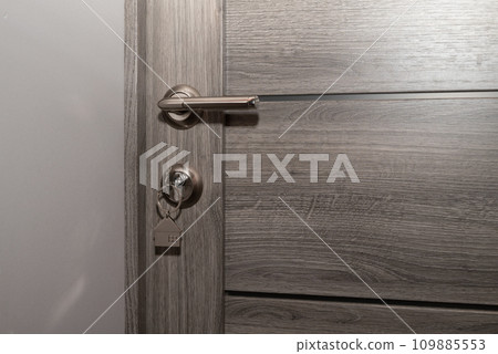 Buy Or Rent concept. Keys with trinket in shape of house in the door keyhole. 109885553