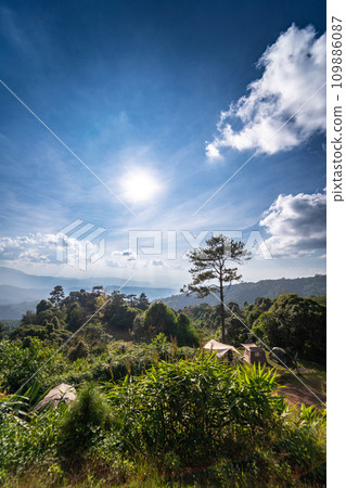 landscape and travel concept with sunlight and cloudy sky with camping tent on mountain 109886087