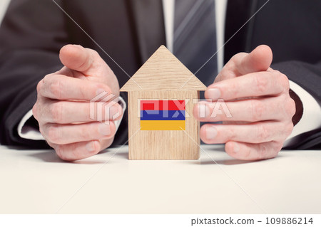 Businessman hand holding wooden home model with Armenian flag. insurance and property concepts 109886214