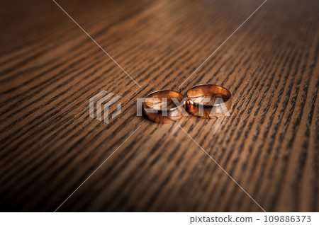 Gold wedding rings on brown background 109886373